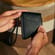 O mână ține un accesoriu husa Ploom Jet Black