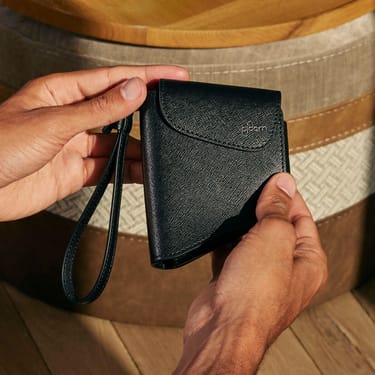 O mână ține un accesoriu husa Ploom  Jet Black
