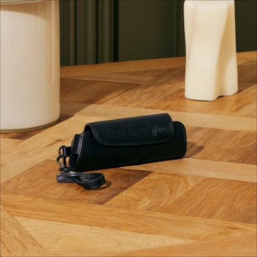 Accesoriul Ploom Aura Etui Jet Black pe o masă
