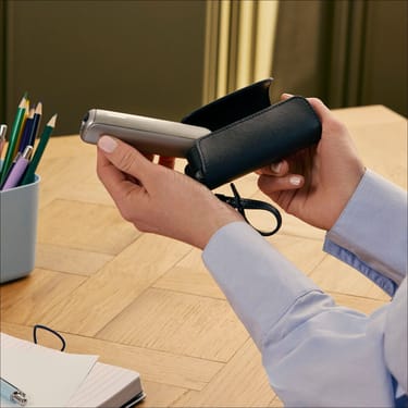 Utilizator care scoate un dispozitiv Ploom AURA din accesoriul etui Jet Black